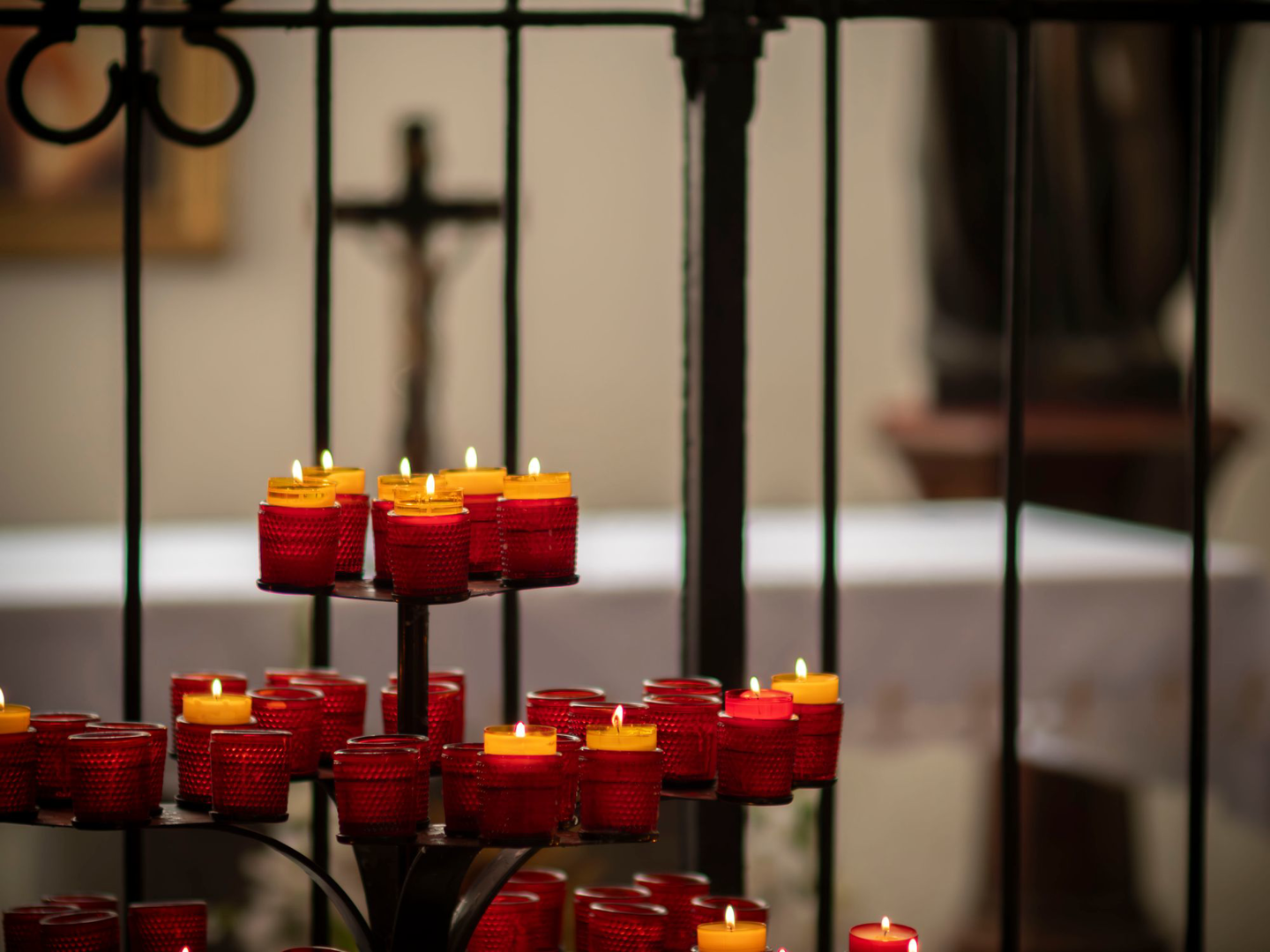 Candles lit on a stand in a dark sanctuary