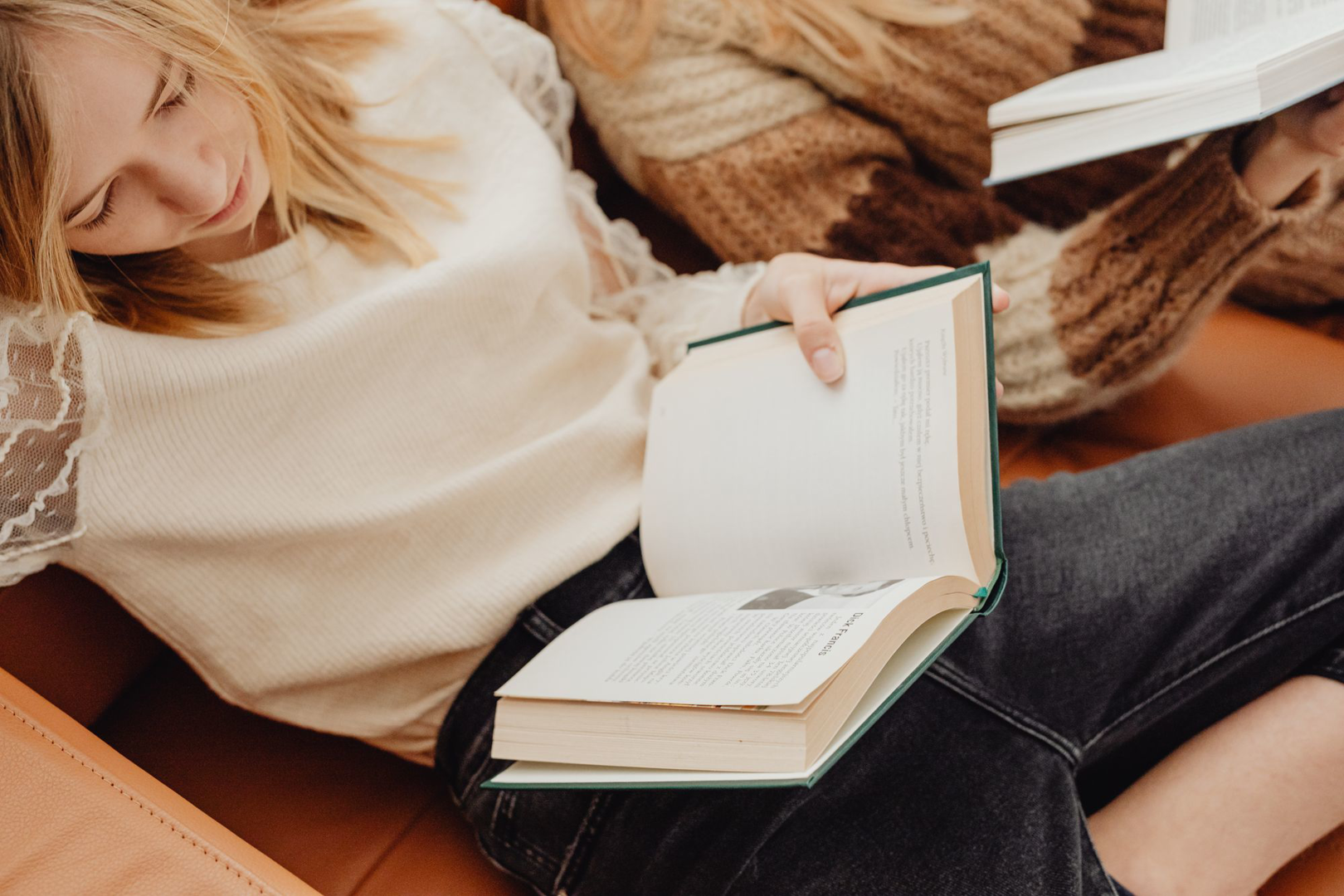A person reading a book beside a cup of coffee